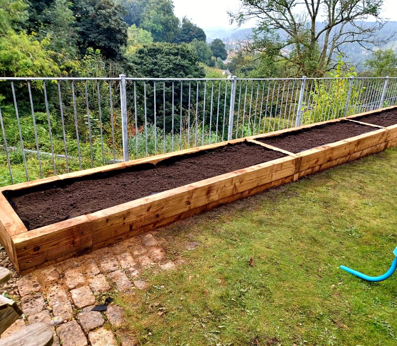 Timber raised garden beds overlooking a green valley
