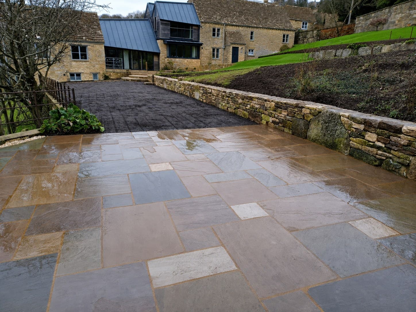 Wet flagstone patio beside a dry stone retaining wall